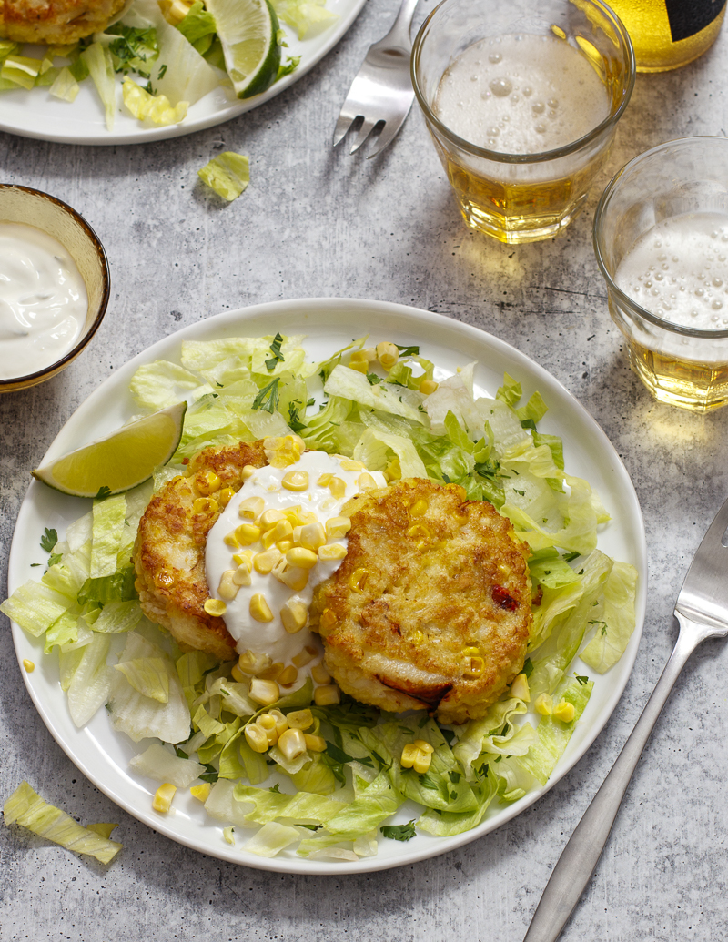 Corn and Crab Cakes with Cilantro and Lime Sour Cream / JillHough.com Corn—both in the cakes and as a garnish—along with cilantro, lettuce, and lime, gives this classic a slight Tex-Mex spin. On the side, serve tortilla chips to scoop up every mouthful. #corn #crabcakes #cilantro #lime #cornandcrab #corncakes