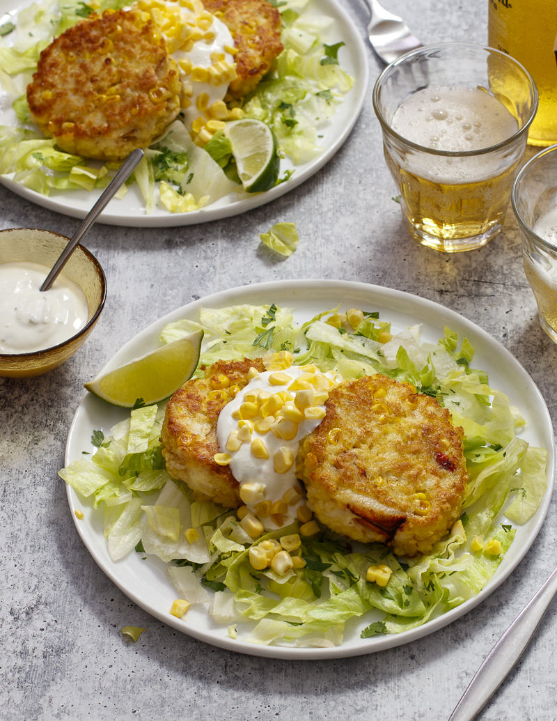 Corn and Crab Cakes with Cilantro and Lime Sour Cream / JillHough.com Corn—both in the cakes and as a garnish—along with cilantro, lettuce, and lime, gives this classic a slight Tex-Mex spin. On the side, serve tortilla chips to scoop up every mouthful. #corn #crabcakes #cilantro #lime #cornandcrab #corncakes